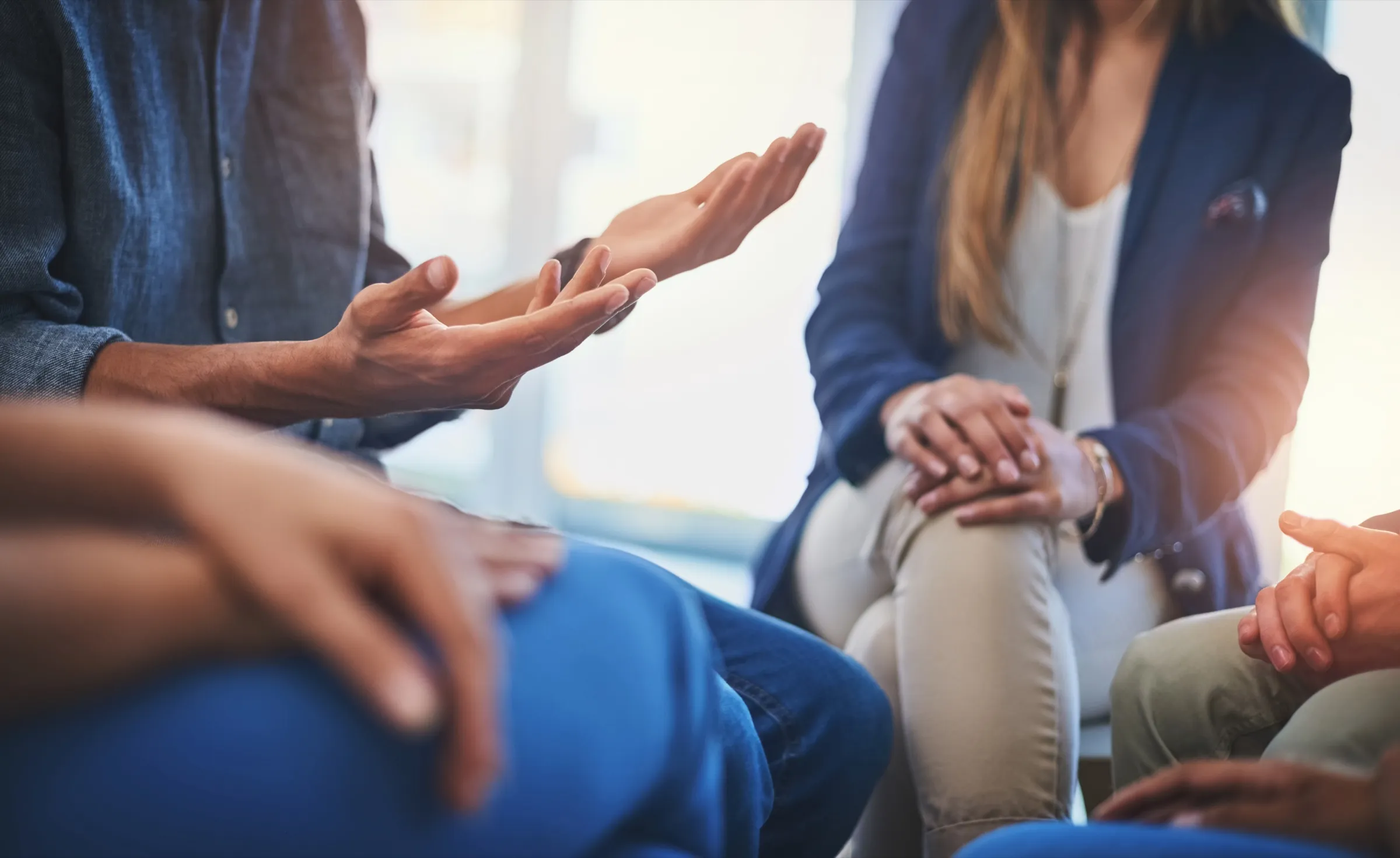 Members of a support group sitting in a circle, one person speaking with open hands