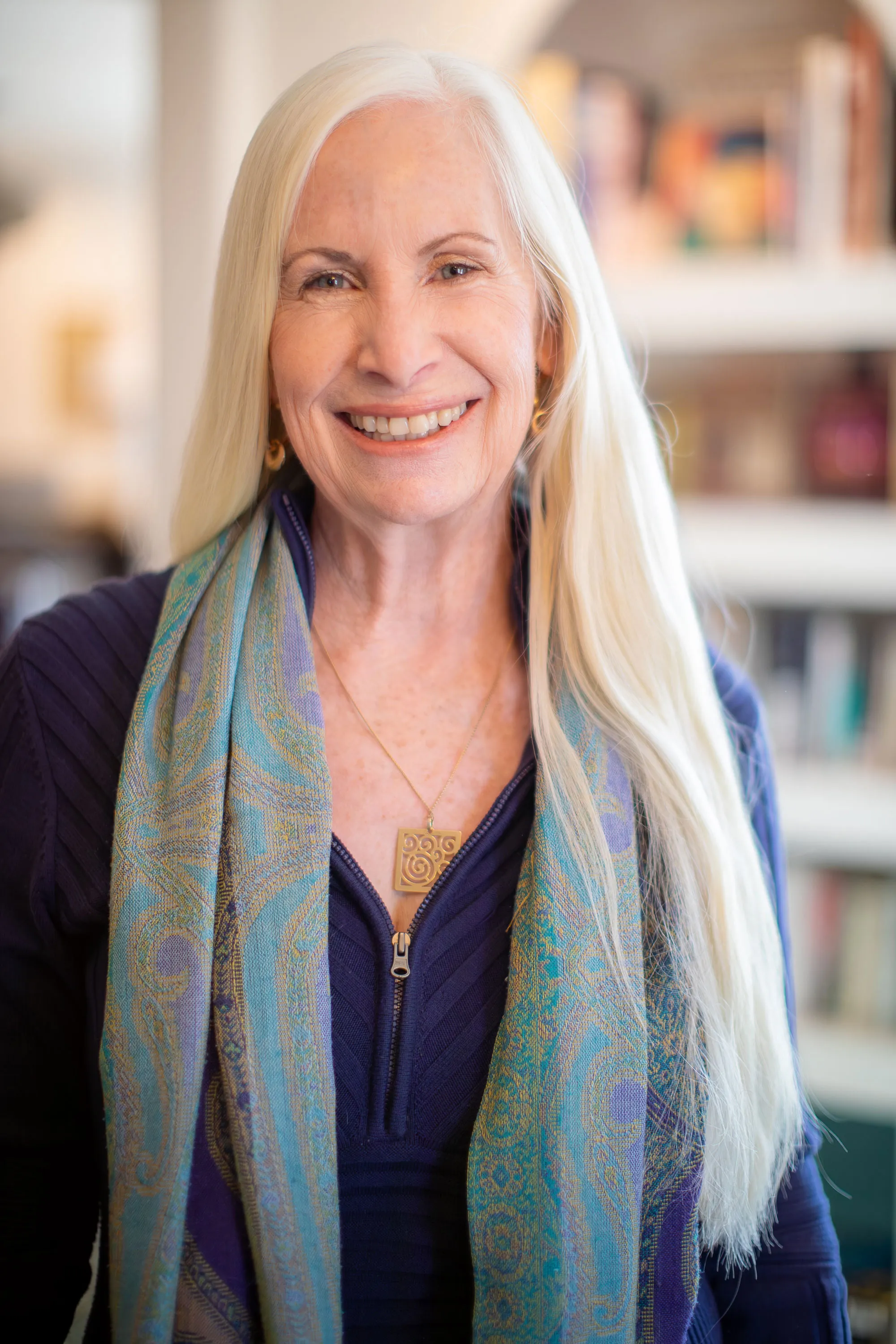 Janice Shayne smiling in front of a bookshelf