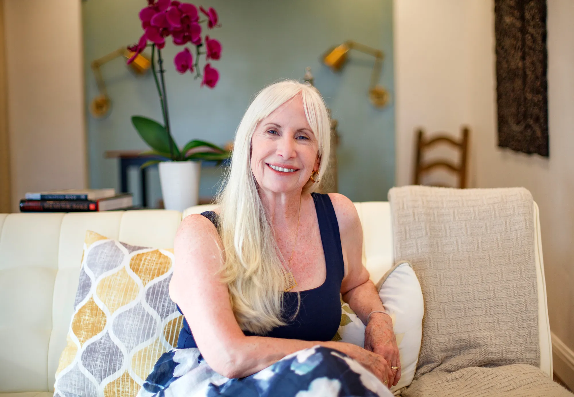 Janice Shayne sitting on the sofa in her office, smiling at the camera