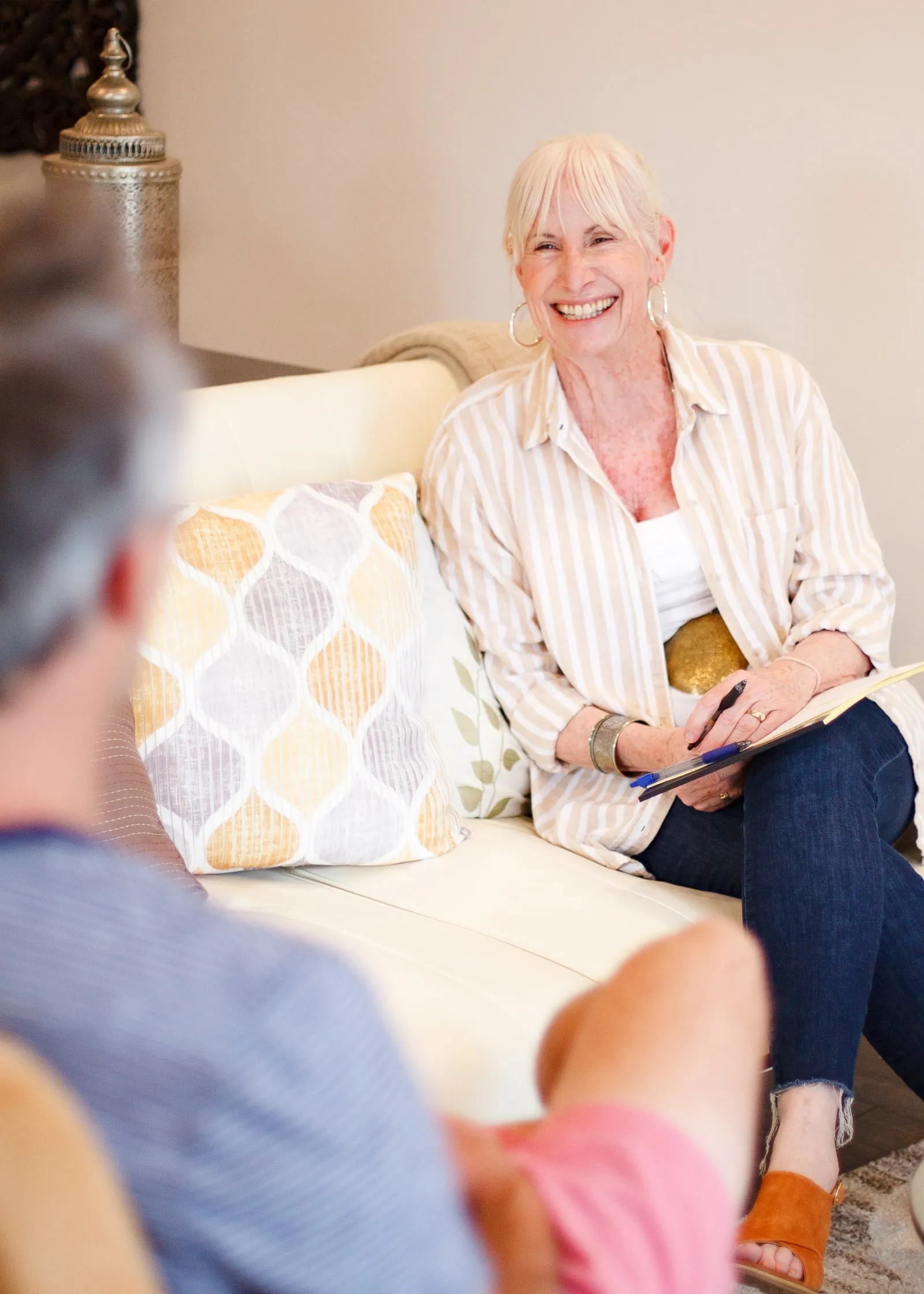 Janice Shayne smiling on the sofa in her office, talking with a client